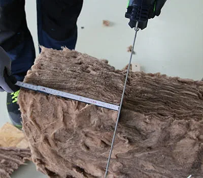 Přiložení měřítka a řezání izolace mezi krokvemi