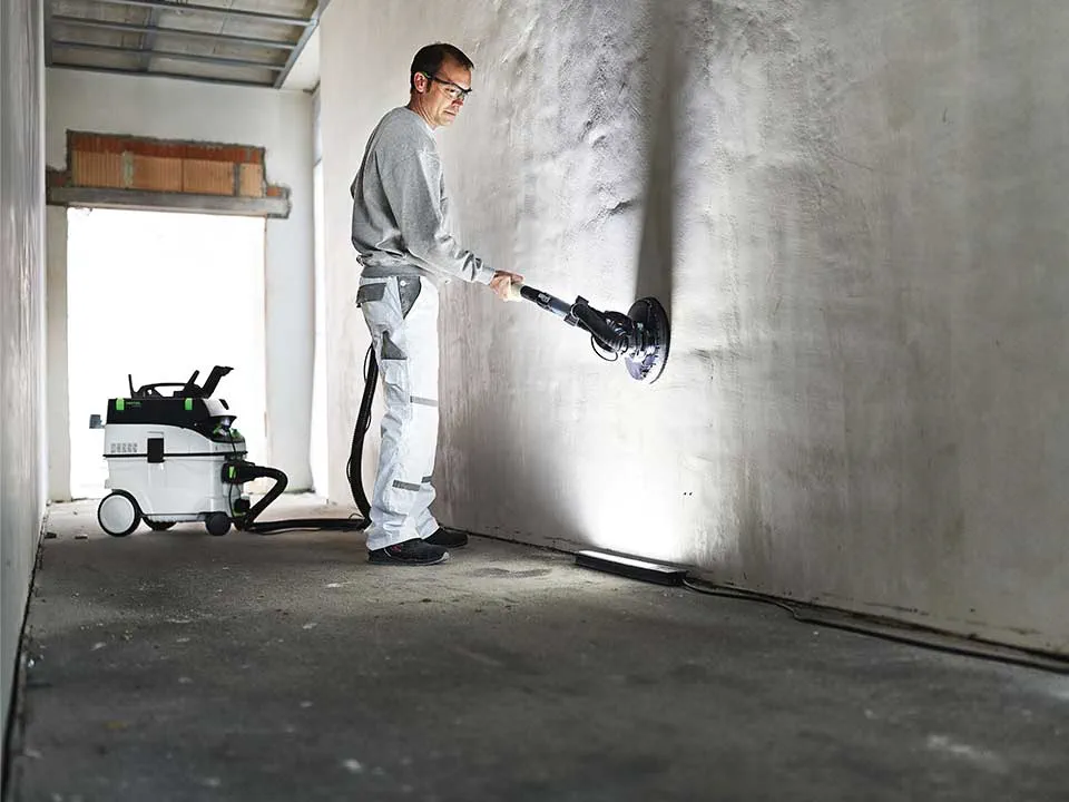 Řemeslník osvětluje stěnu pomocí Kontrolního světla a brousí ji.